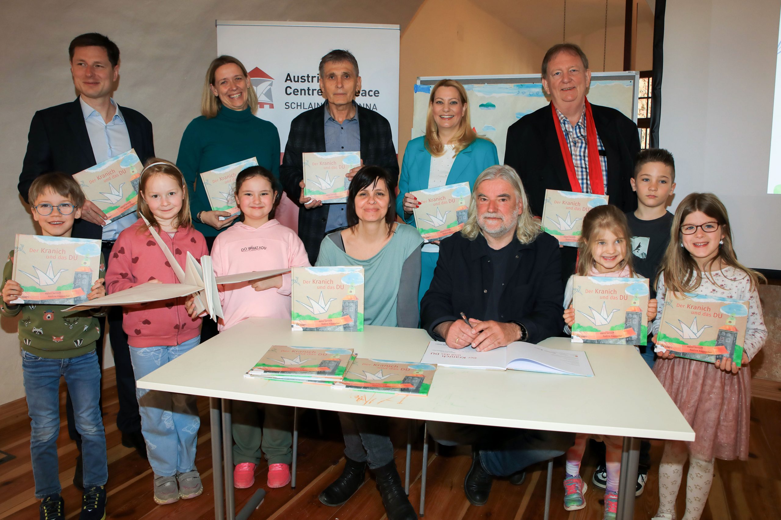 Friedenserziehung von klein auf: Präsentation des Kinderbuchs „Der Kranich und das DU“ Präsentierten das Kinderbuch „Der Kranich und das DU“ im Rahmen eines Workshops mit Kindern der Volkschule Statdtschlaining: Bildungslandesrätin Daniela Winkler (2. Reihe, 2.v.r.), Autor Heinz Janisch (1. Reihe), Illustratorin und Grafikerin Nadine Kappacher (1. Reihe), Klaus Novak (2. Reihe, 3.v.r.), Leiter des Instituts für Fort- und Weiterbildung an der Privaten Pädagogischen Hochschule Burgenland, Horst Horvath (2. Reihe, 1.v.r.), Verlagshaus edition lex liszt 12, Tobias Lang (2. Reihe 1.v.l.), dem neuen Direktor des Austrian Centre for Peace und Direktorin Eva Schitter (2. Reihe, 2.v.l.) , Volksschule Stadtschlaining