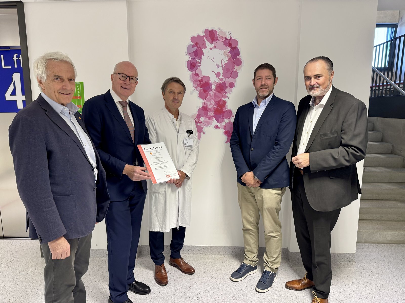 Zertifikatübergabe im Brustgesundheitszentrum der Klinik Güssing: Kriwanek, Lax, Willhuber, Uranitsch und LH Doskozil vor einer rosa Schleife