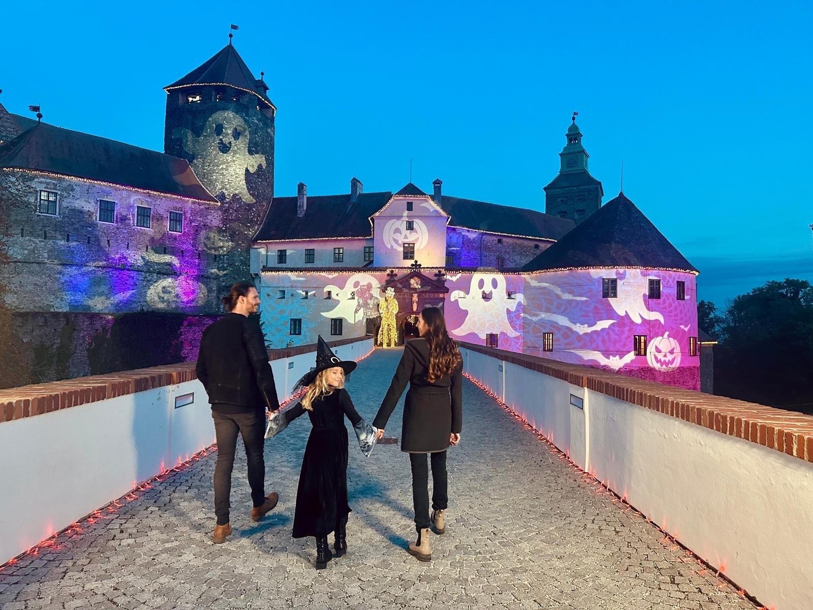 Familie mit verkleidetem Kind auf dem Weg zur beleuchteten Burg Schlaining bei Burg Geflüster zu Halloween